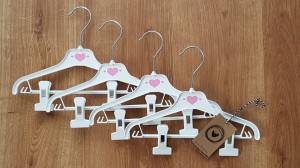 Wieszaki niemowlęce z poprzeczką. Biało-różowe wieszaki z klipsami. Wieszaki do niemowlęcej garderoby.