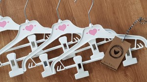 Wieszaki niemowlęce z poprzeczką. Biało-różowe wieszaki z klipsami. Wieszaki do niemowlęcej garderoby.