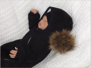 Oryginalny kombinezon wiosenno-jesienny dla niemowlaka, noworodka. Włóczkowy kombinezon dla niemowląt. Ciepły kombinezon z kapturem i pomponem futerkowym. Unikalny czarny kombinezon na wyjście ze szpitala, na chrzest. Must have wyprawki dla noworodka.