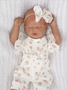 Muślinowy kombinezon niemowlęca z falbankami. Przewiewny dziewczęcy rampers. Kombinezon na lato z opaską dla niemowlaka. Biały rampers muślinowy w kwiaty dla małej dziewczynki.