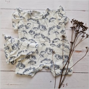 Muślinowy kombinezon niemowlęca. Przewiewny dziewczęcy rampers. Kombinezon na lato z czapeczką dla niemowlaka. Biały rampers muślinowy w kwiaty dla małej dziewczynki.