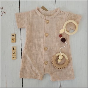 Muślinowy rampers niemowlęcy dla chłopca. Przewiewny chłopięcy rampers z drewnianymi guzikami.  Rampers muślinowy w kolorze  beżowym dla małego chłopczyka.