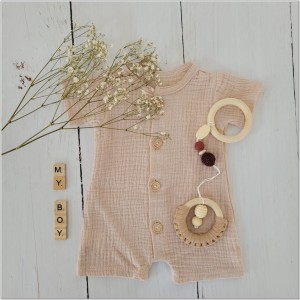 Muślinowy rampers niemowlęcy dla chłopca. Przewiewny chłopięcy rampers z drewnianymi guzikami.  Rampers muślinowy w kolorze  beżowym dla małego chłopczyka.