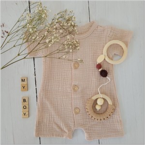 Muślinowy rampers niemowlęcy dla chłopca. Przewiewny chłopięcy rampers z drewnianymi guzikami.  Rampers muślinowy w kolorze  beżowym dla małego chłopczyka.