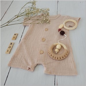 Muślinowy rampers niemowlęcy dla chłopca. Przewiewny chłopięcy rampers z drewnianymi guzikami.  Rampers muślinowy w kolorze  beżowym dla małego chłopczyka.