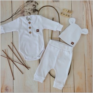 Prążkowany zestaw dla niemowlaka. Komplet całoroczny w  kolorze białym. Prążkowane spodnie w komplecie z body i czapką dla niemowlaka.