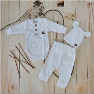 Prążkowany zestaw dla niemowlaka. Komplet całoroczny w  kolorze białym. Prążkowane spodnie w komplecie z body i czapką dla niemowlaka.