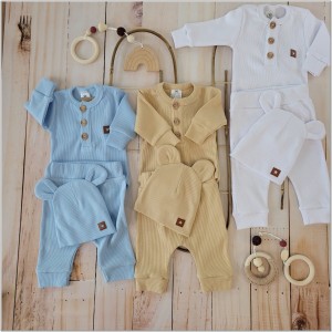 Prążkowany zestaw dla niemowlaka. Komplet całoroczny w  kolorze białym. Prążkowane spodnie w komplecie z body i czapką dla niemowlaka.