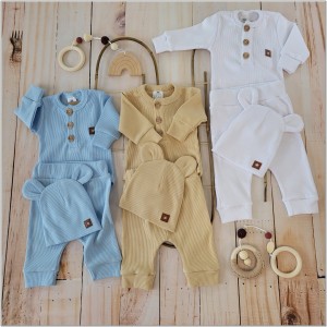 Prążkowany zestaw dla niemowlaka. Komplet całoroczny w  kolorze białym. Prążkowane spodnie w komplecie z body i czapką dla niemowlaka.