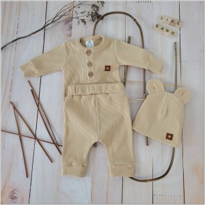 Prążkowany zestaw dla niemowlaka. Komplet całoroczny w  kolorze beżowym. Prążkowane spodnie w komplecie z body i czapką dla niemowlaka.
