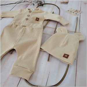 Prążkowany zestaw dla niemowlaka. Komplet całoroczny w  kolorze beżowym. Prążkowane spodnie w komplecie z body i czapką dla niemowlaka.