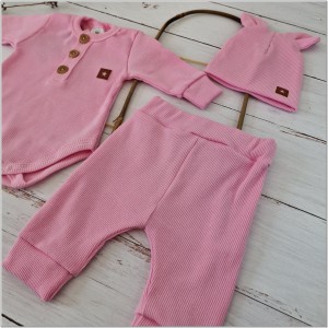 Prążkowany zestaw dla niemowlaka. Komplet całoroczny w  kolorze różowym. Prążkowane spodnie w komplecie z body i czapką dla niemowlaka.
