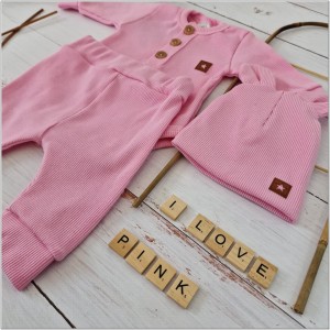 Prążkowany zestaw dla niemowlaka. Komplet całoroczny w  kolorze różowym. Prążkowane spodnie w komplecie z body i czapką dla niemowlaka.