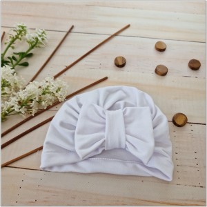 Cienka niemowlęca czapka prążkowana. Czapka z kokardą dla dziewczynki. Dresowa czapka z kokardą dla dziewczynki w kolorze białym.